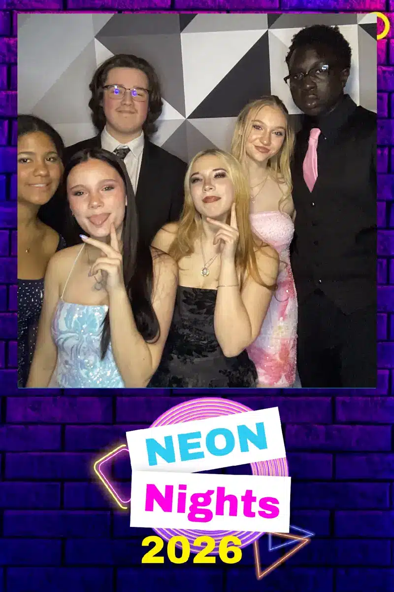 Group of students in formal attire at Neon Nights 2026 prom photo booth with black and white geometric backdrop